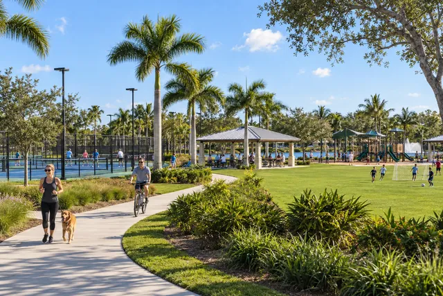 Paved path through a public regional park with pavilions, sports courts, playing fields and palms